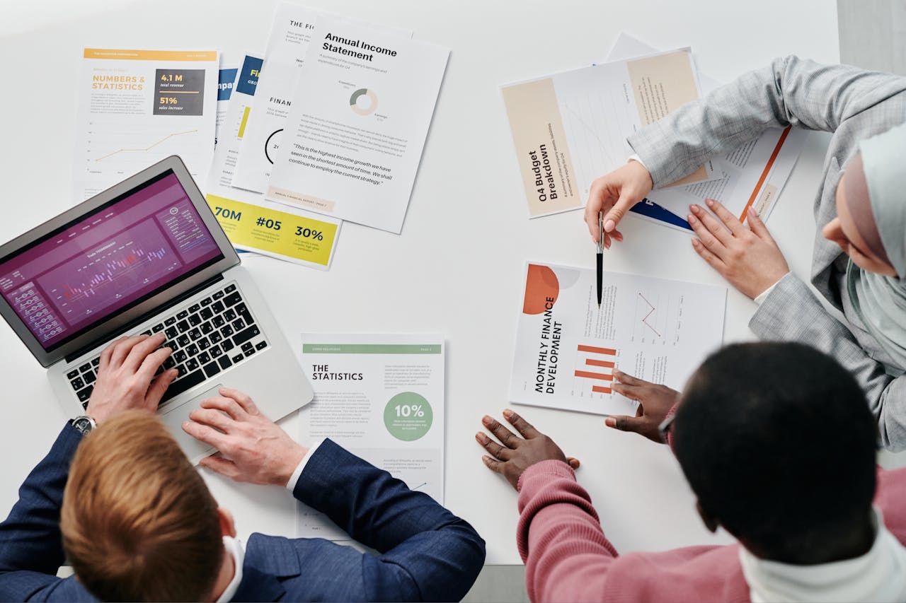 Business meeting with professionals discussing financial reports and graphs at a work desk.